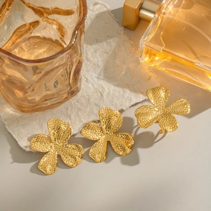 Detailed macro view of three gold-colored vintage textured flower rings on a warm background