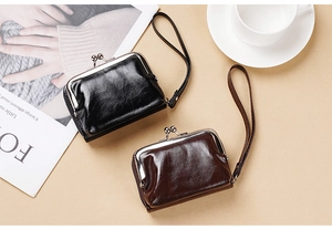 Dettaglio di portamonete vintage in pelle cerata nera e marrone con chiusura in metallo