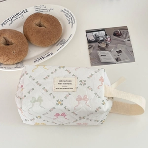 Détail de la trousse de maquillage matelassée avec nœuds colorés et poignée tissée