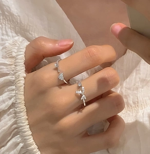Close-up of sparkling zircon heart and bow knot open rings on a hand in a sweet style