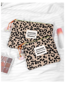 Vista dettagliata della borsa in tela leopardata con zip arancione e ciondolo a ciambella