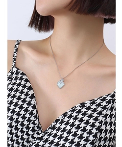 Gros plan du collier étoile avec pendentif en coquillage sur vêtement pied-de-poule