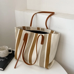 Minimalistische gestreifte große Shopper-Tasche mit braunen Lederriemen auf Tisch
