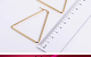 Detailed view of large gold triangle earrings with ruler showing 5cm size scale