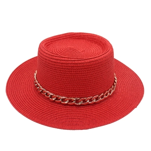 Detail of red straw flat top boater hat with a decorative gold chunky chain band
