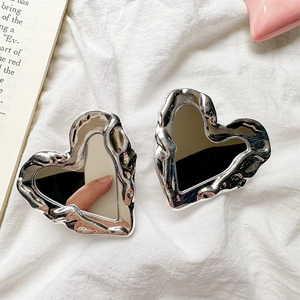Detail of silver heart-shaped mirror phone grip with liquid metal frame on white fabric