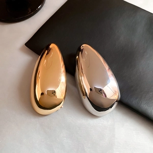 Macro shot of liquid teardrop pins in gold and silver finish on contrast background