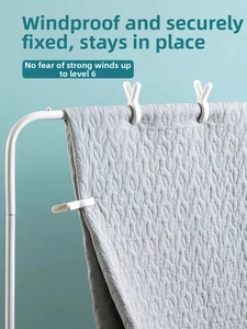 White heavy duty plastic laundry clips securely holding a thick quilt on a drying rack