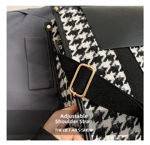 Detail showing the adjustable wide fabric strap and golden buckle on houndstooth bag