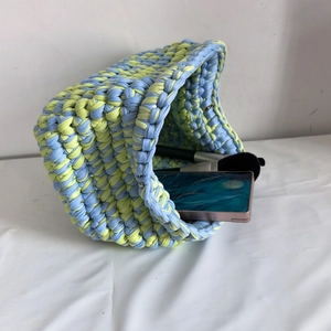 Detail of colorful woven crochet bag showing blue and light green fabric knit texture