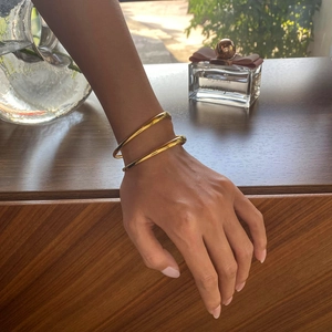 Bracelet jonc doré à double couche porté au poignet dans un décor élégant et raffiné