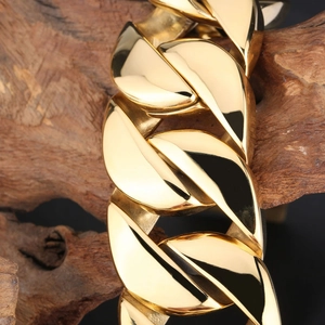 Heavy 18k gold plated stainless steel Cuban link bracelet on a textured wood branch