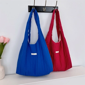 Detail of blue and burgundy quilted tote bags with square labels hanging on a wall
