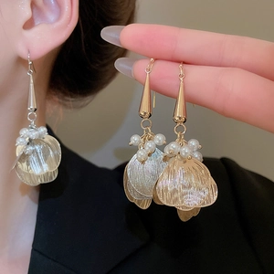 Detail of long hollow petal earrings with pearls and mixed gold and silver finish