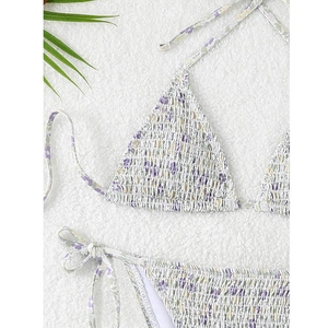 Detail of smocked floral bikini fabric with lilac and green patterns on white backdrop