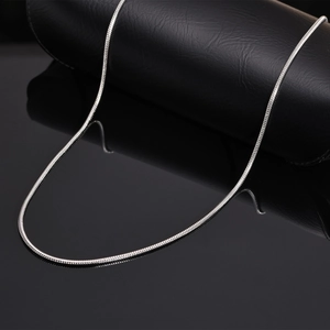 Polished silver stainless steel snake chain necklace for women on black reflective surface
