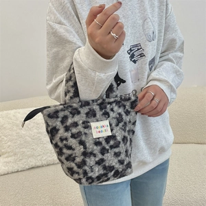 Detail of leopard print plush handbag with zipper and white brand label logo on soft fur