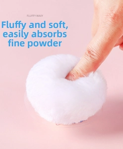 Close-up of soft fluffy white baby powder puff being pressed to show plush texture