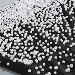 Detailed macro view of high-quality white pearls sewn on elegant black evening dress fabric