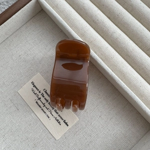 Close-up of translucent amber brown 5-tooth hair claw clip on a jewelry tray