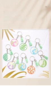 Detail of acrylic keychain with tropical floral print, metal ring, and mint green tassel