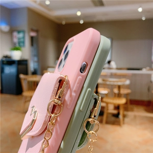Close-up of pink and green crossbody phone cases with gold heart card holder and chain