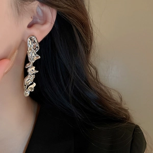 Close-up of silver irregular lava design earring with polished metallic flowing texture