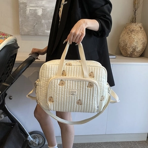Sac à langer beige matelassé avec broderie ours, poignées et bandoulière réglable