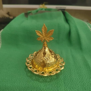 Detailed macro view of a golden Arabic incense burner with intricate floral engravings