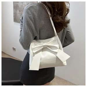 Detail view of a white tote bag with a large decorative bow and elegant leather texture