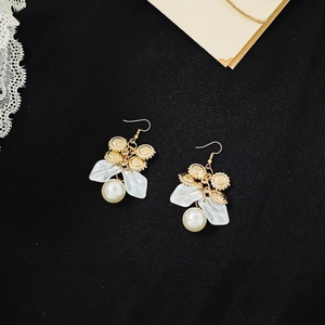 Detail of vintage French gold earrings with white resin petals and a large pearl drop