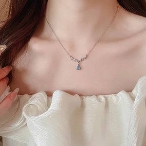 Close-up of a silver chain featuring a blue water-drop pendant and sparkling zircons