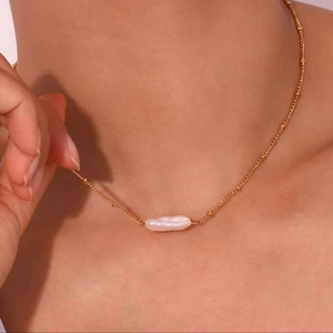 Detail of baroque freshwater pearl pendant on a gold satellite chain for women