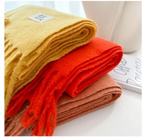 Detail of stacked yellow, orange and russet wool scarves with knitted texture and tassels