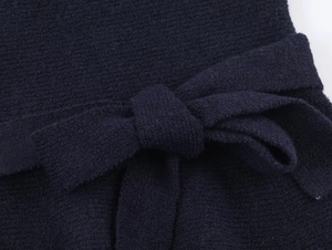 Close-up of the navy blue knitted top featuring a self-tie bow belt and texture detail