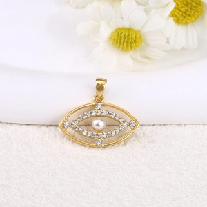 Macro shot of gold plated evil eye pendant with clear zircons and a central pearl accent