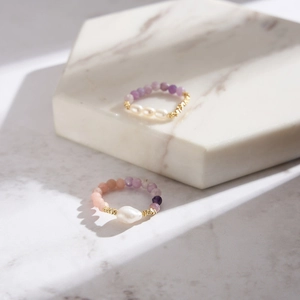 Macro shot of stretch rings with pink Australian opal, lilac beads and baroque pearls