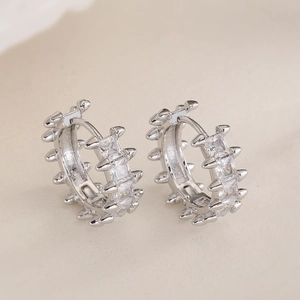 Silver hoop earrings with square zircons and spiked details in industrial aesthetic style