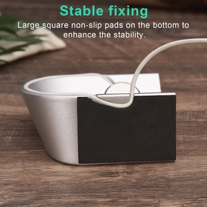 Silver aluminum Apple Watch stand with non-slip base on a wooden desk setup