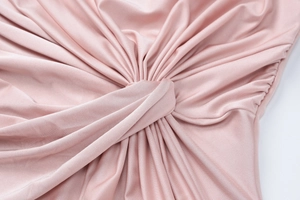 Detail of elegant dusty pink evening dress showing silk-like fabric with ruching and knot design