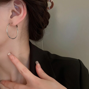 Gros plan de boucles d'oreilles créoles argentées sur un mannequin en blazer noir