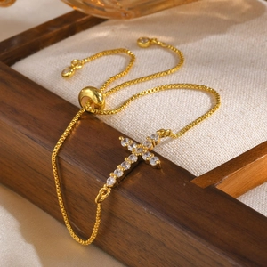 Detail of adjustable gold box chain bracelet with sparkling zircon cross on wood tray