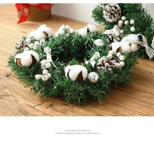 Detail of Christmas wreath with cotton, pine cones, and bells on a wooden background