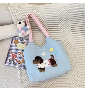 Close-up of heart-quilted blue shoulder bag with pink handles and cute dachshund embroidery