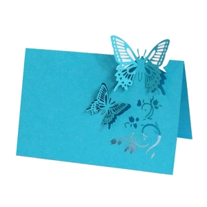 Macro view of sky blue laser-cut butterfly place card with intricate floral hollow design