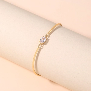 Elegant gold bangle with rhombic zircon centerpiece on a neutral display stand