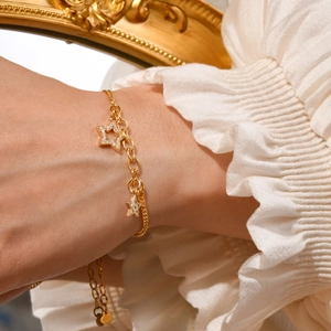 Detail of 18K gold-plated bracelet featuring zircon-encrusted star charms on white lace