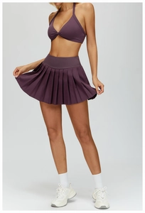 Detail of high-waist pleated tennis skirt and halter neck yoga bra in plum purple