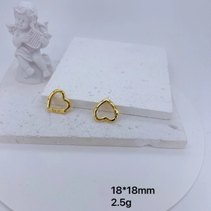 Detail of gold heart earrings with micro-inlaid cubic zirconia on a white stone pedestal