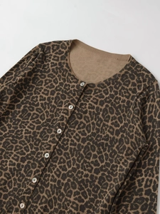 Detail of leopard print knit cardigan featuring round neck and white buttons on brown fabric